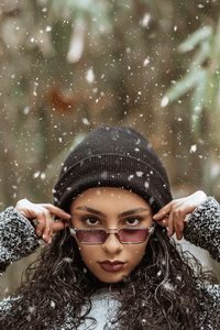 Zima, kobieta w czapce trzymająca się za okulary